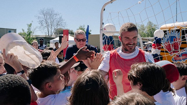 Sir David Beckham shown greeting children in front of a soccer net